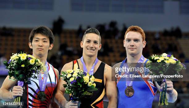 Gold medalist Marcel Nguyen of Germany celebrates on the podium alongside silver medalist Kazihito Tanaka of Japan and bronze medlaist Dan Purvis of...