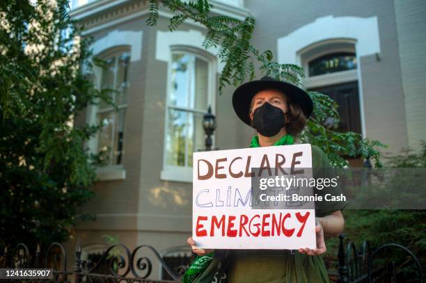 Climate change activist stands outside the home of Sen. Jim Inhofe while participating in a "Tour of Shame", marching to the homes of senators they...