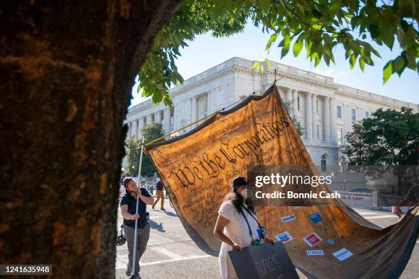 Members of Extinction Rebellion DC, ShutDown DC and Arm in Arm DC carry a giant model of the constitution, altered to say We The Corporations during...