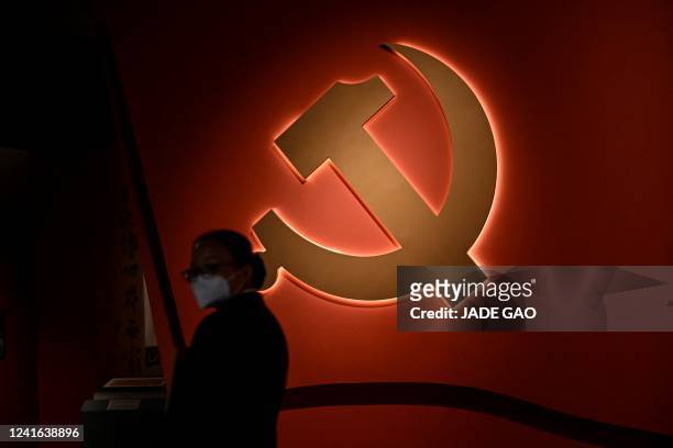 Woman stands in front of the party emblem at an exhibition themed on the Chinese Communist Party, at the National Museum in Beijing on July 1, 2022.