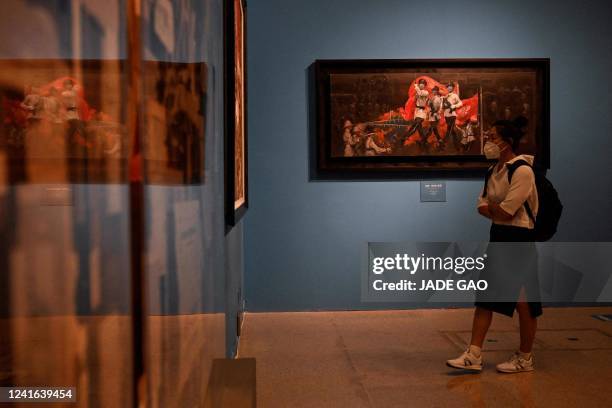 Woman stands next to "Brilliant Hong Kong in Synchronous Steps with the Motherland by artists Wang Xuexian, Yan Yaya and Wang Xueru as she visits an...