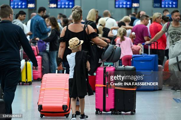 Woman and a child together with other passengers queue at the check-in counter at Duesseldorf International Airport , western Germany on July 1,...