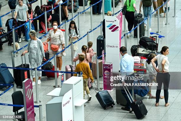 Passengers queue at the check-in counter of Eurowings at Duesseldorf International Airport , western Germany on July 1, 2022. - Airlines and airports...