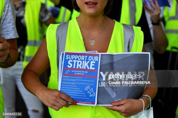 Ryanair employee holds flyers reading "Support our strike" as they protest at the Terminal 2 of El Prat airport in Barcelona on July 1, 2022. - At...