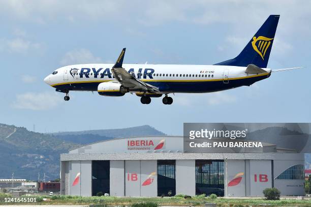 Ryanair Boeing 737-8AS aircraft flies over an Iberia hangar as it lands at El Prat airport in Barcelona on July 1, 2022. Nine flights to and from...