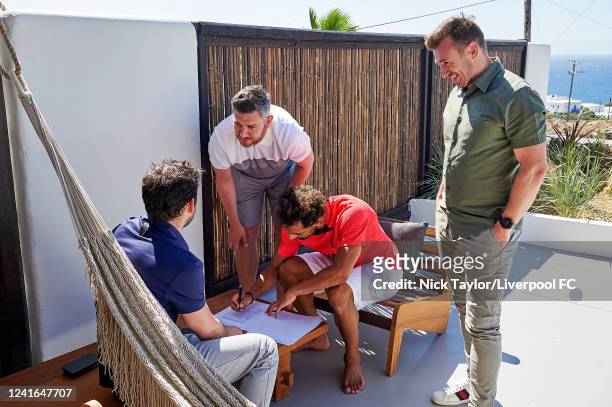 Mohamed Salah of Liverpool signs a contract extension with Ramy Abbas Issa, Jonathan Bamber and Julian Ward, while on holiday on June 19, 2022 in...