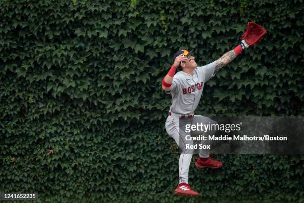 Jarren Duran of the Boston Red Sox leaps into the ivy in attempt to catch a triple hit by Nelson Velazquez of the Chicago Cubs during the fifth...