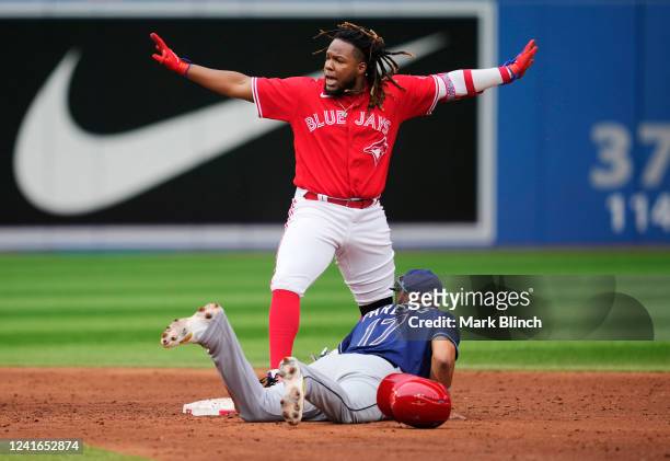 Vladimir Guerrero Jr. #27 of the Toronto Blue Jays reacts at second base after hitting a two RBI double as Isaac Paredes of the Tampa Bay Rays tries...