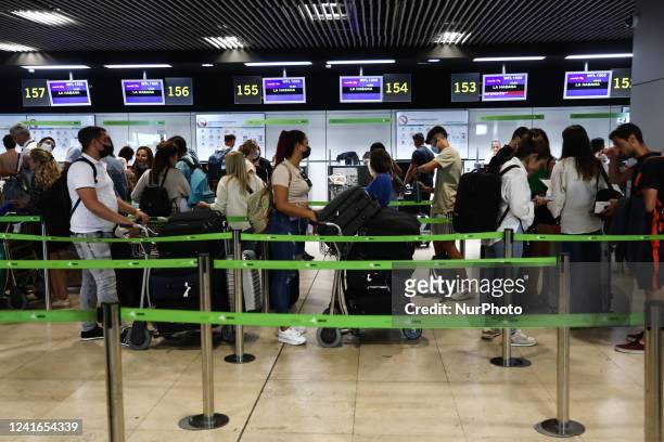 Passengers wait in the line at the Barajas Airport in Madrid on July 1, 2022.