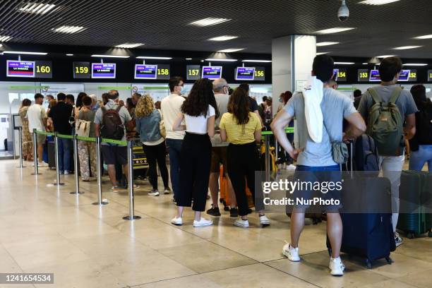 Passengers wait in the line at the Barajas Airport in Madrid on July 1, 2022.