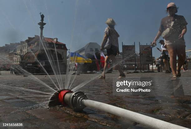 People walk next to the water sprinkler instaled in the Castle Square in Warsaw. Friday was the day of the culmination of the heat wave in Poland....