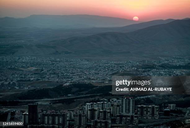 This picture taken on July 1, 2022 shows the sun setting behind the mountains from Mount Azmar, on the eastern outskirts of Iraq's northeastern city...