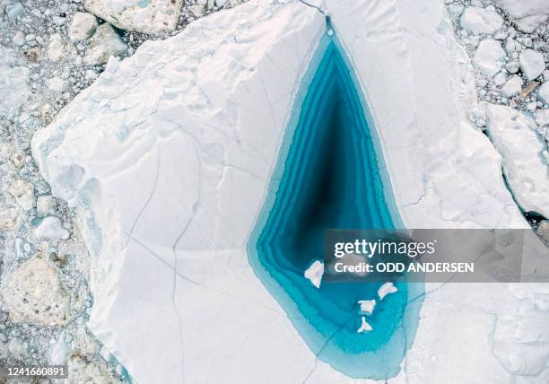 Picture taken on June 29, 2022 with a drone shows turquoise water in a large melt hole on the top of an iceberg in the Disko Bay, Ilulissat, western...