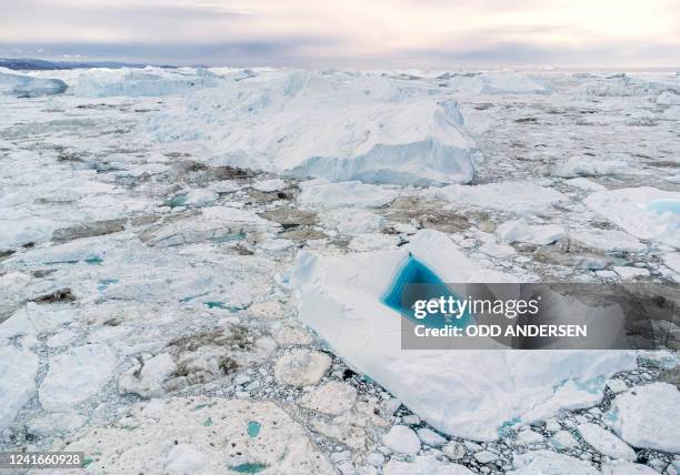 Picture taken on June 29, 2022 with a drone shows turquoise water in a large melt hole on the top of an iceberg in the Disko Bay, Ilulissat, western...