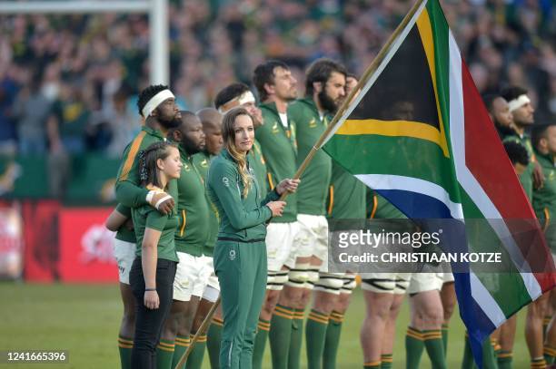South African Olympic swimming gold medallist Tatjana Schoenmaker holds the South African national flag as the South African rugby team line up to...
