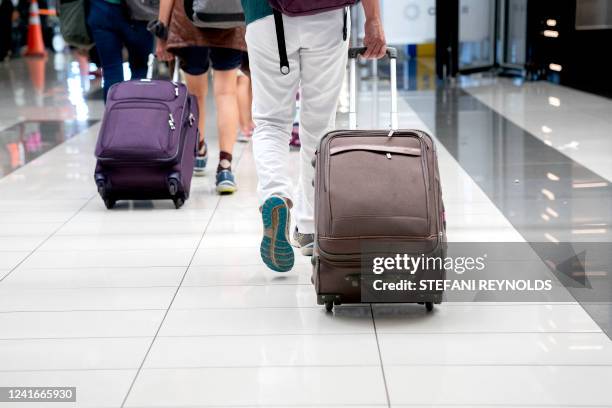 Travelers walk through Ronald Reagan Washington National Airport in Arlington, Virginia, on July 2, 2022. US airlines are bracing customers for what...