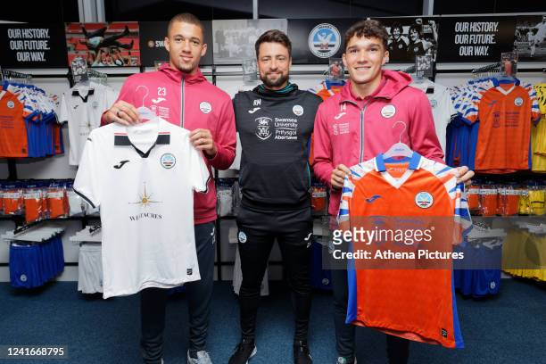 Nathan Wood, manager Russell Martin and Kyle Joseph pose with home and away shirts during the re-opening of the Swansea City club shop City at...