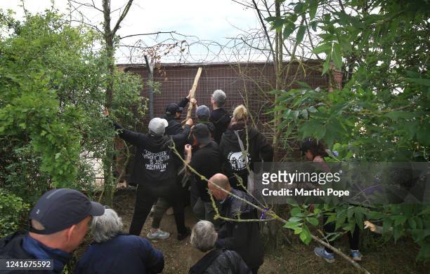 Animal activists use a log to try to dislodge a protective screen MBR security officers have installed to cover a hole in the fence on July 2, 2022...