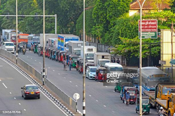 Motorists queue along a street to buy fuel at a fuel station in Colombo on July 3, 2022.