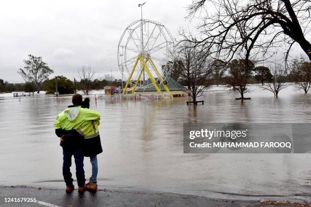 People look at a flooded park due to torrential rain in the Camden suburb of Sydney on July 3, 2022. Thousands of Australians were ordered to...