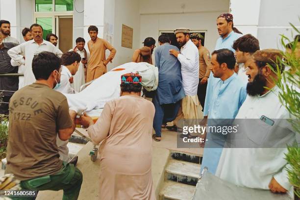 Graphic content / People carry the dead body of a passenger on a stretcher, who died in a bus accident, outside a hospital in Zhob district of...