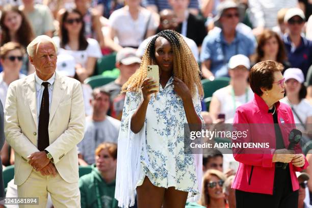 Player Venus Williams uses her smartphone flanked by Swedish former tennis player Bjorn Borg and US former world No. 1 tennis player Billie Jean King...