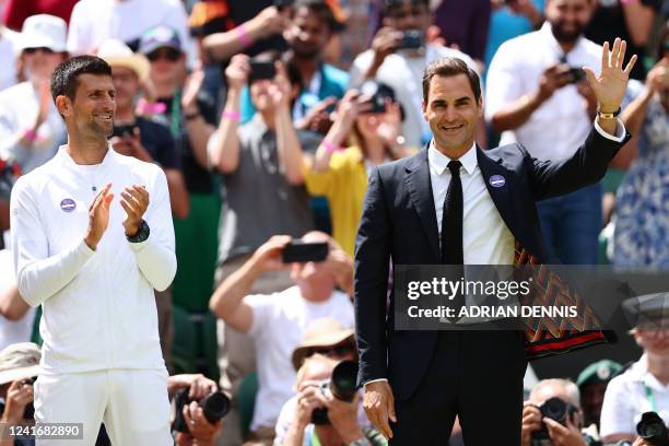 Swiss tennis player Roger Federer waves next to Serbia's Novak Djokovic as they take part in the Centre Court Centenary Ceremony, on the seventh day...