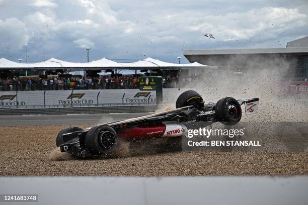 The overturned car of Alfa Romeo's Chinese driver Zhou Guanyu skids through the gravel after a crash at the start of the Formula One British Grand...