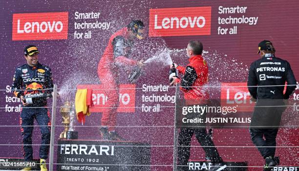 Second-placed Red Bull Racing's Mexican driver Sergio Perez and Third-placed Mercedes' British driver Lewis Hamilton spray winner Ferrari's Spanish...