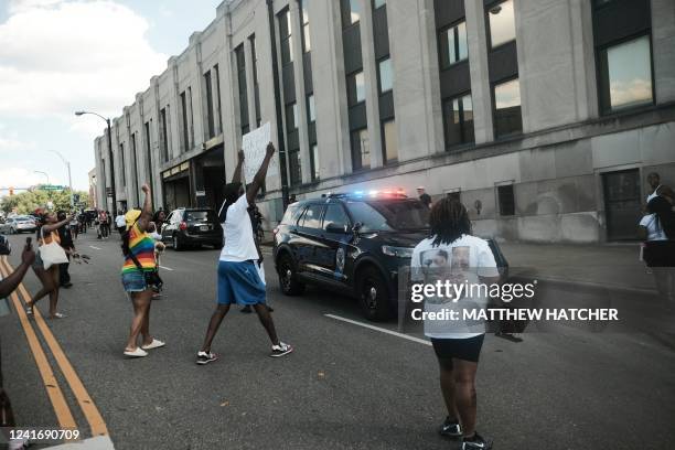 Demonstrators wave signs around a police car as they gather outside Akron City Hall to protest the killing of Jayland Walker, shot by police, in...