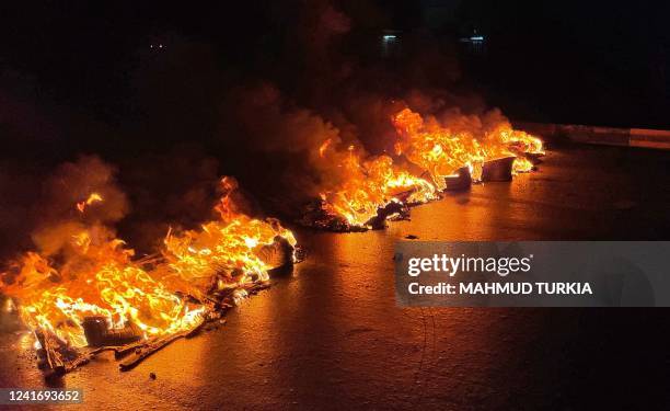 Picture taken in the early hours of July 4 shows burning tyres blocking roads during overnight protests in the Libyan capital Tripoli. - Libya's...