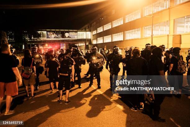 Demonstrators face troopers in riot gear as police deployed tear gas and stun grenades to clear the area around Akron City Hall and Akron Police...