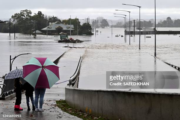 Residents look out toward flooded buildings next to the old Windsor Bridge along the overflowing Hawkesbury River in the northwestern Sydney suburb...