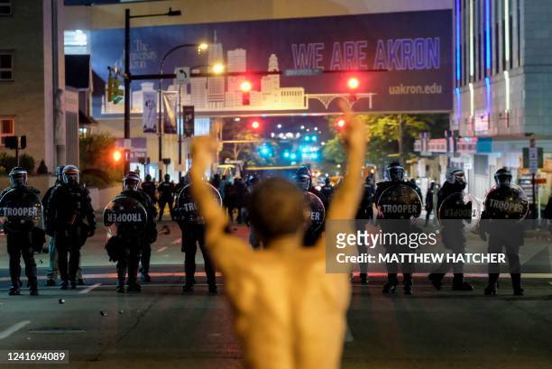 Man gestures toward troopers in riot gear as police deployed tear gas and stun grenades to clear the area around Akron City Hall and Akron Police...