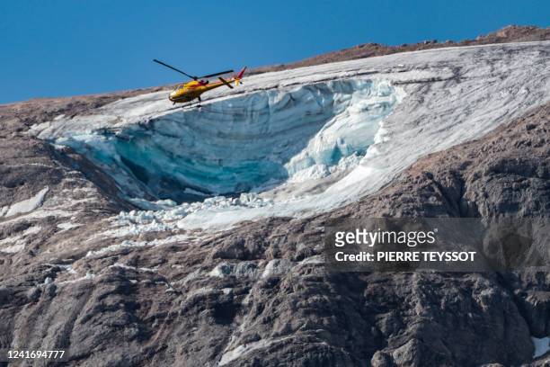 Rescue helicopter flies on July 4, 2022 over the glacier that collapsed the day before on the mountain of Marmolada, the highest in the Dolomites,...