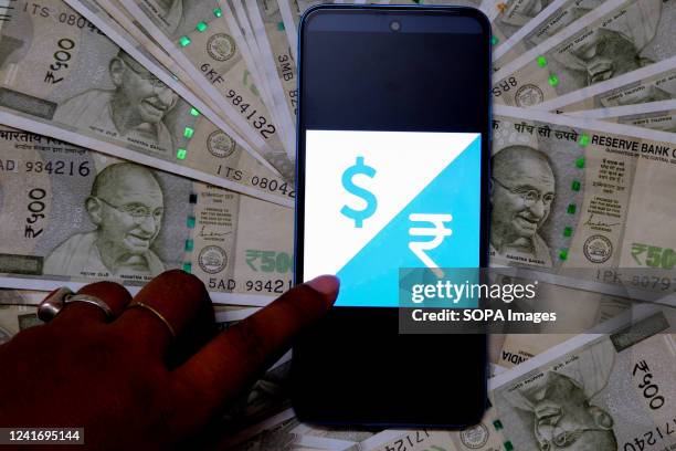 In this photo illustration, a logo of the US Dollar and Indian rupee is displayed on a smartphone screen with Indian Currency note illustrations in...