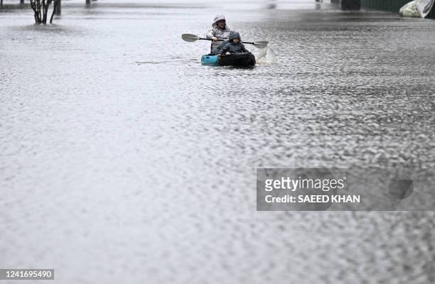 People kayak along a flooded street from the overflowing Hawkesbury river due to torrential rain in the Windsor suburb of Sydney on July 4, 2022.