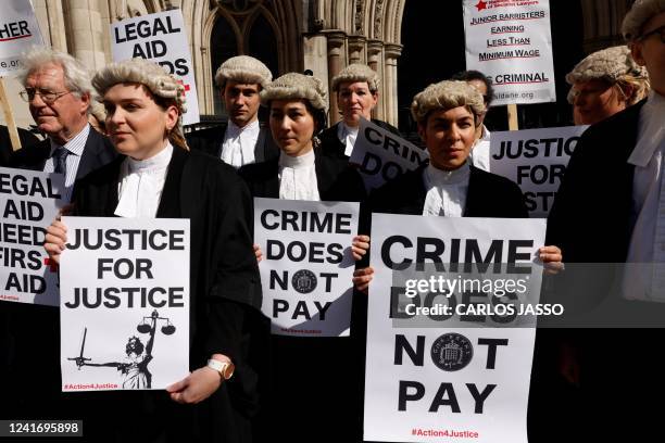 Senior criminal lawyers hold placards outside the Royal Courts of Justice in London on July 4, 2022 as they go on strike in a dispute over pay. -...