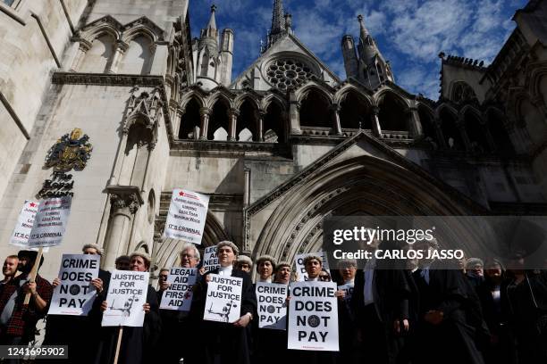 Senior criminal lawyers hold placards outside the Royal Courts of Justice in London on July 4, 2022 as they go on strike in a dispute over pay. -...
