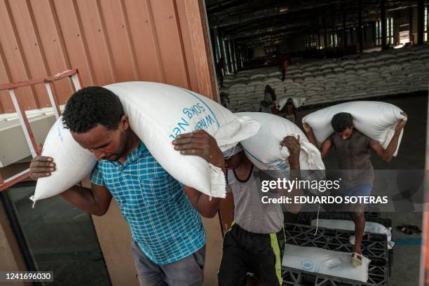 Workers carry sacks of grain in a warehouse of the World Food Programme in the city of Abala, Ethiopia, on June 9, 2022. - The Afar region, the only...