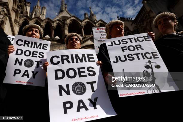 Senior criminal lawyers hold placards outside the Royal Courts of Justice in London on July 4, 2022 as they go on strike in a dispute over pay. -...