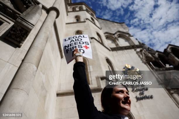 Lawyer holds a placard outside the Royal Courts of Justice in London on July 4, 2022 as they go on strike in a dispute over pay. - Barristers have...