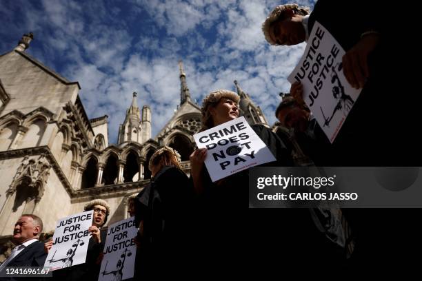 Senior criminal lawyers hold placards outside the Royal Courts of Justice in London on July 4, 2022 as they go on strike in a dispute over pay. -...