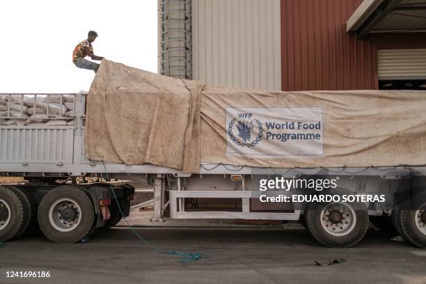 Worker covers a truck full of sacks of grain in a warehouse of the World Food Programme in the city of Abala, Ethiopia, on June 09, 2022. - The Afar...