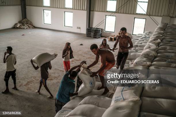 Workers carry sacks of grain in a warehouse of the World Food Programme in the city of Abala, Ethiopia, on June 9, 2022. - The Afar region, the only...