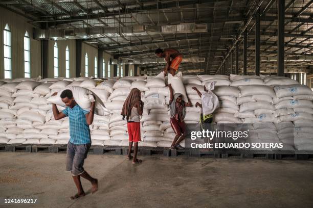 Workers carry sacks of grain in a warehouse of the World Food Programme in the city of Abala, Ethiopia, on June 9, 2022. - The Afar region, the only...