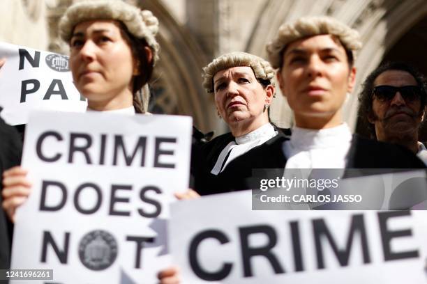 Senior criminal lawyers hold placards outside the Royal Courts of Justice in London on July 4, 2022 as they go on strike in a dispute over pay. -...