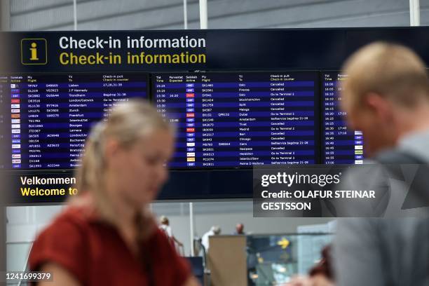 Passengers stand in front of a flight information board in the departure hall at Copenhagen Kastrup airport, Denmark, on July 4, 2022 after it became...
