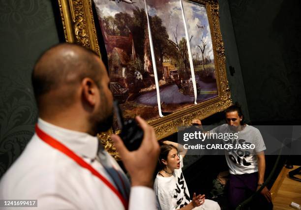 Activists from the 'Just Stop Oil' campaign group, with hands glued to the frame of the painting 'The Hay Wain' by English artist John Constable, but...