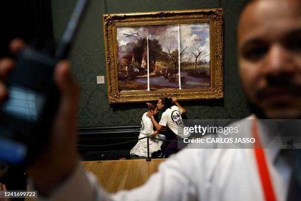 Activists from the 'Just Stop Oil' campaign group, with hands glued to the frame of the painting 'The Hay Wain' by English artist John Constable, but...